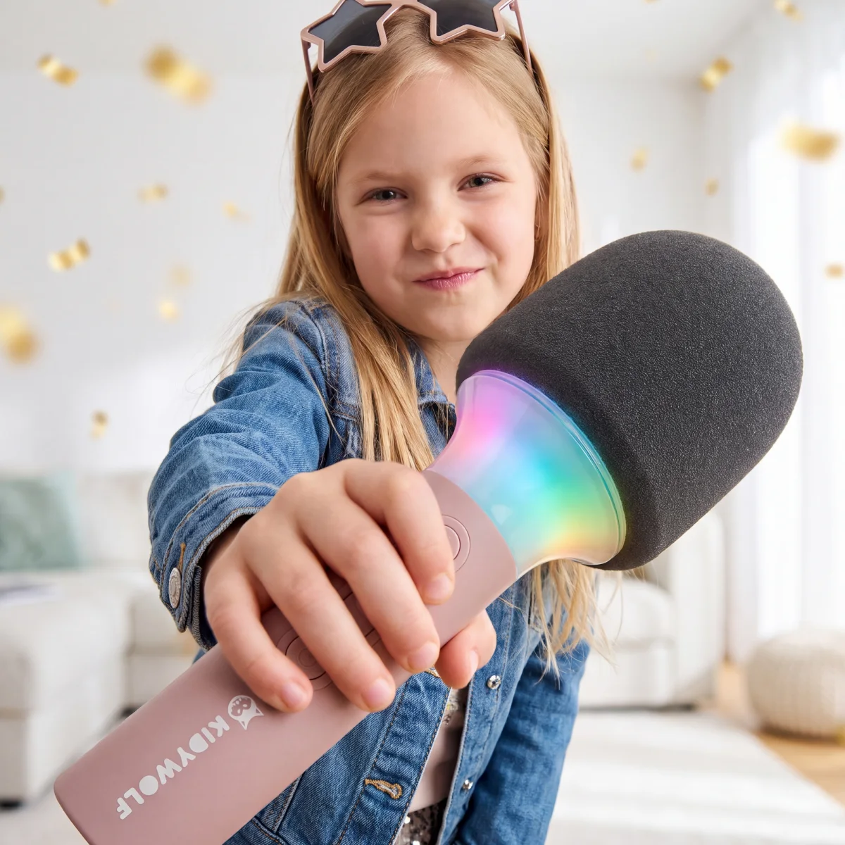 Kislány a kamera felé nyújtja a világító, rózsaszín Kidywolf karaoke mikrofont